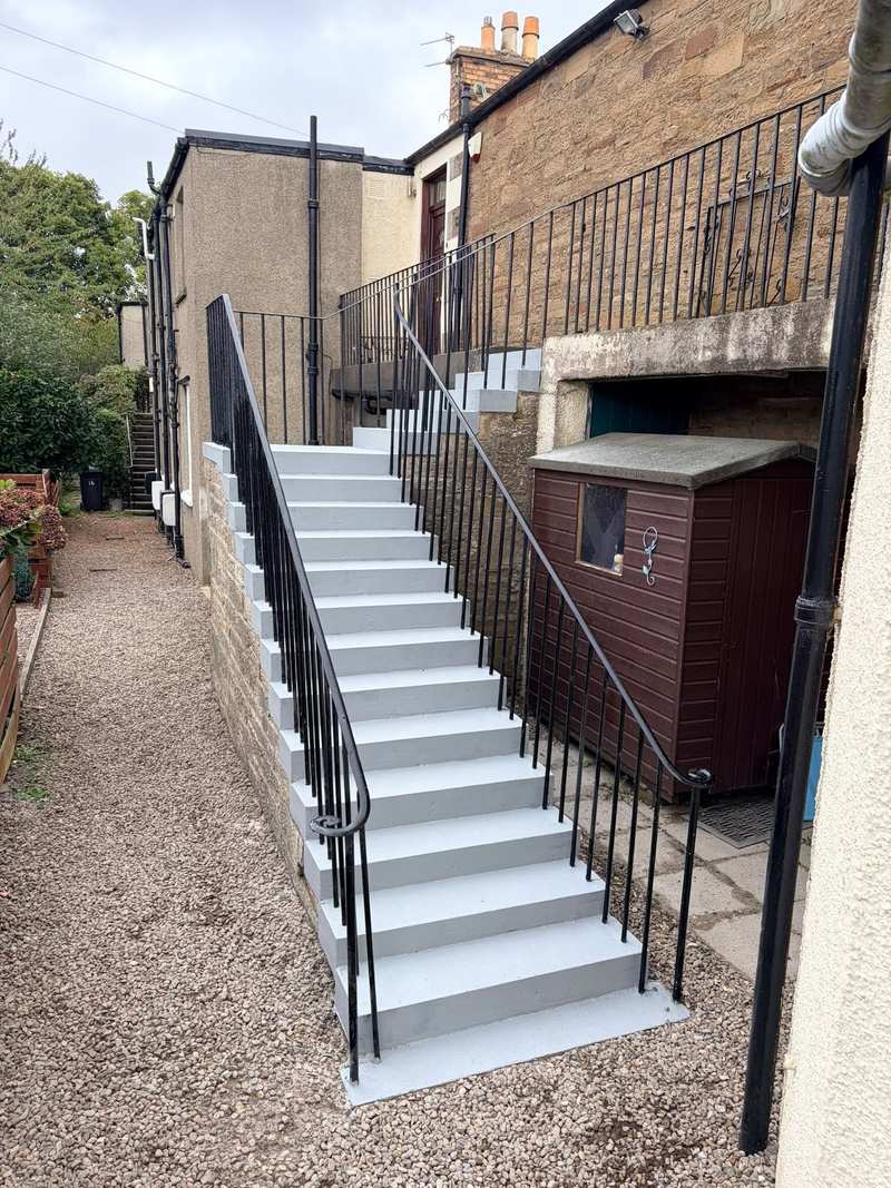 Refurbished external concrete stair with crisp grey treads and risers, seen from the foot of the stair