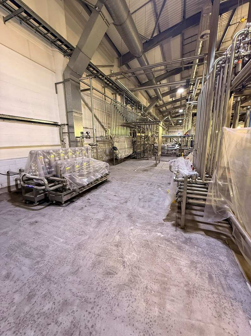 Prepared concrete floor in a process plant hall before resin, with stainless pipework and wrapped plant