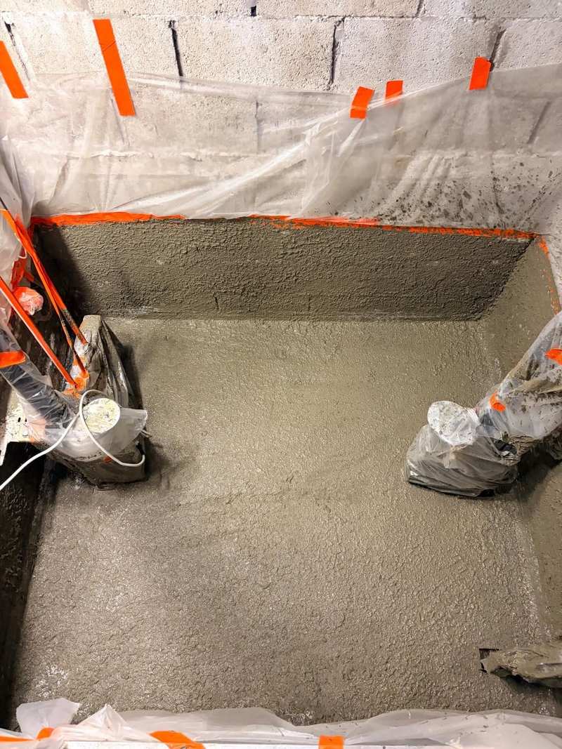 Lift shaft pit with cementitious waterproofing across the floor and up the walls, lift equipment protected in polythene
